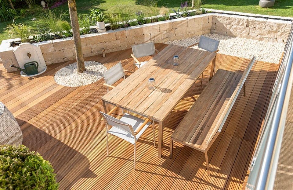 Angolo di un giardino con decking in teak, tavolo e panca in legno