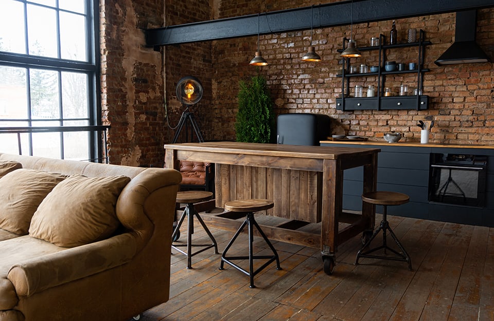 Open space in stile industrial con cucina e salotto, grande finestrone e molto legno