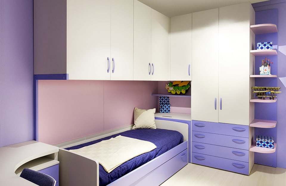 Dormitorio con estructura combinada de cama y armario, todo en tonos blancos y morados. Moradas son también las paredes de la habitación mientras que el suelo es de color blanco;