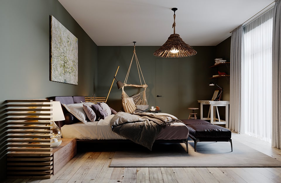 Camera da letto in stile rustico-moderno. Il pavimento è in parquet grigio rustico, il soffitto bianco e le pareti verde scuro. Il letto ha una struttura metallica nera essenziale e ai due lati dei comodini bassi in legno rustico a forma di parallelepipedo, con divisorio “a persiana” che si alza fino a un terzo della parete. Dietro al letto c'è un quadro astratto sul verde, e da un lato del letto una seduta in tessuto stile amaca, appesa al soffitto. Il lampadario è in legno rustico. In fondo alla stanza una scrivania vintage bianca e rustica, con sopra delle mensole. Una grande finestra che arriva fino a terra illumina la stanza, che è vista di lato