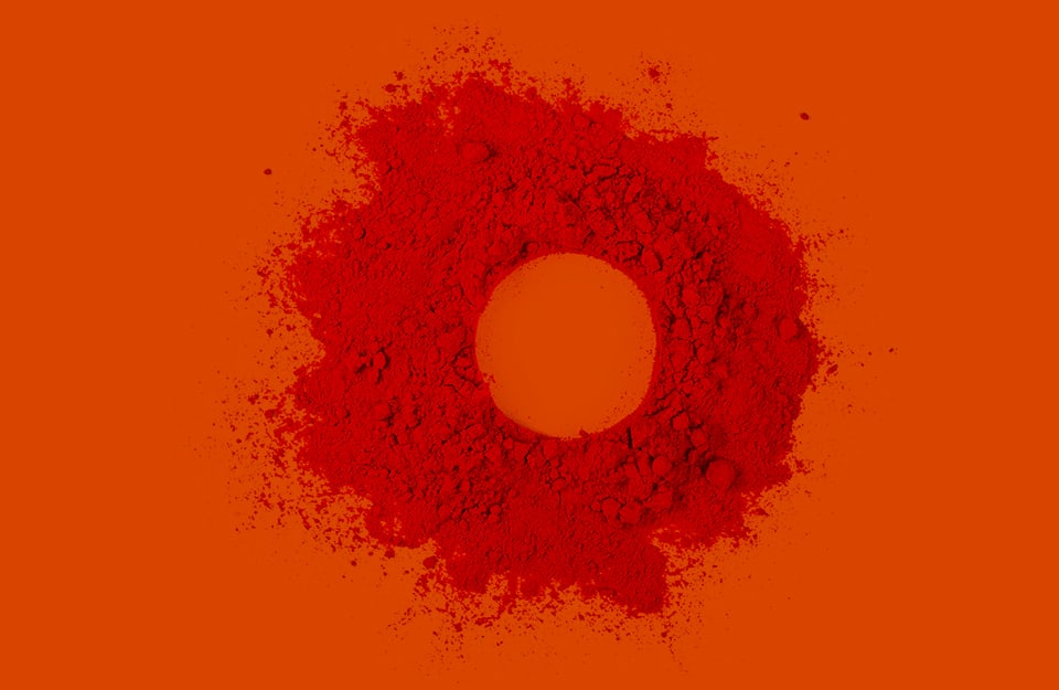 Polvere di pigmento rosso terroso su sfondo rosso-arancio