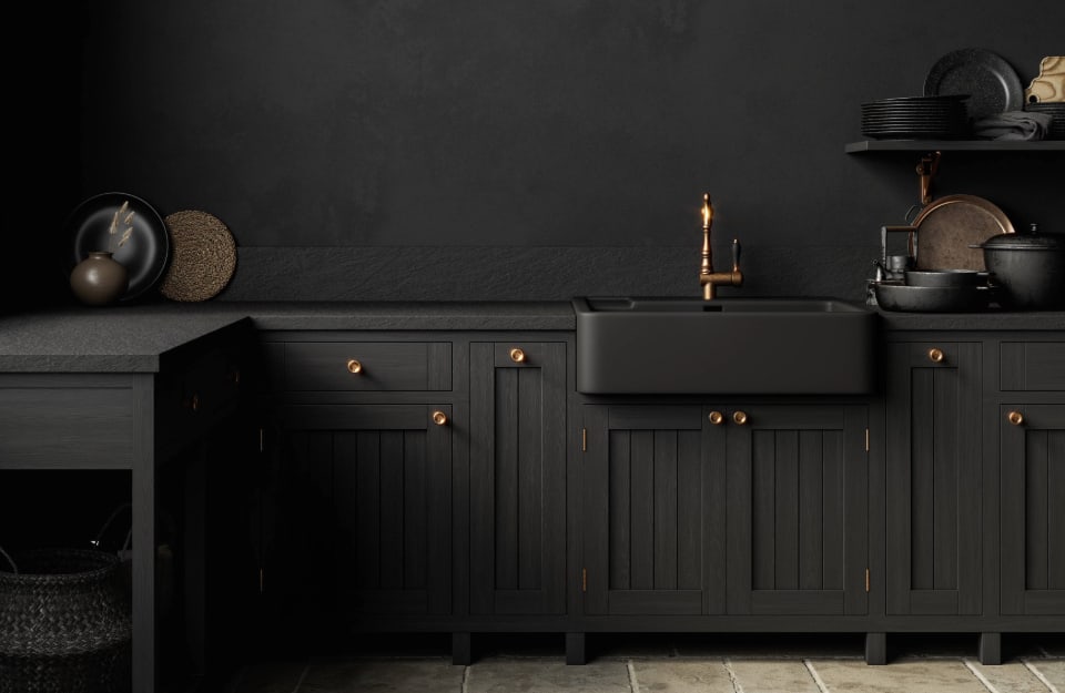 Cucina nera rustica con dettagli color rame e lavandino nero, su parete nera