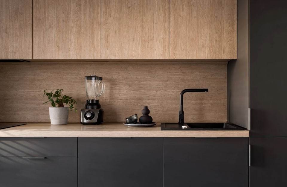 Dettaglio di una cucina nera con pensili e pianale in legno