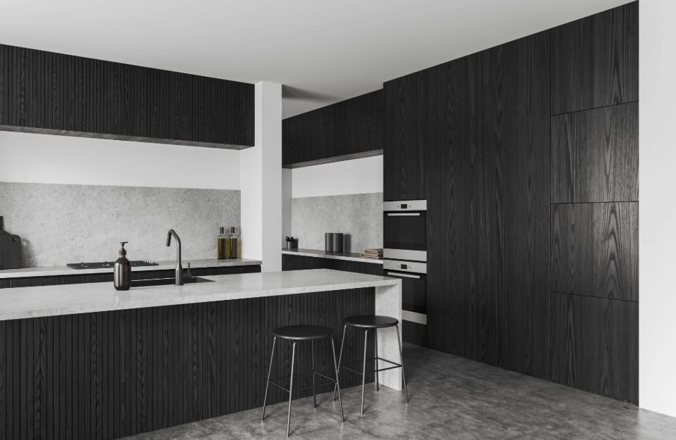 Grande cucina nera con penisola con mobili neri con venature a vista, piani di lavoro in marmo bianco, soffito e pareti bianche e pavimento effetto marmo