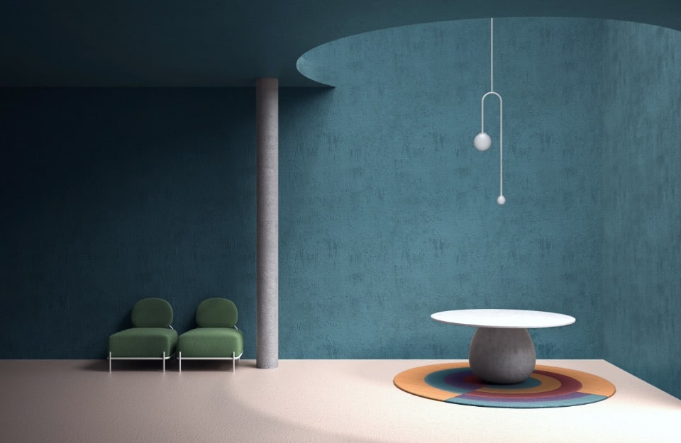 Una gran sala con paredes azules: a la derecha, el techo está abierto en forma circular y la luz entra por ahí, iluminando una mesa redonda con una alfombra circular con motivos geométricos amarillos, rojos y azules. En la habitación también hay una columna blanca y dos sillas antiguas modernas de tela verde