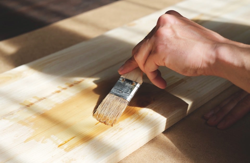 Un uomo sta applicando dell'impregnante a una tavola di legno