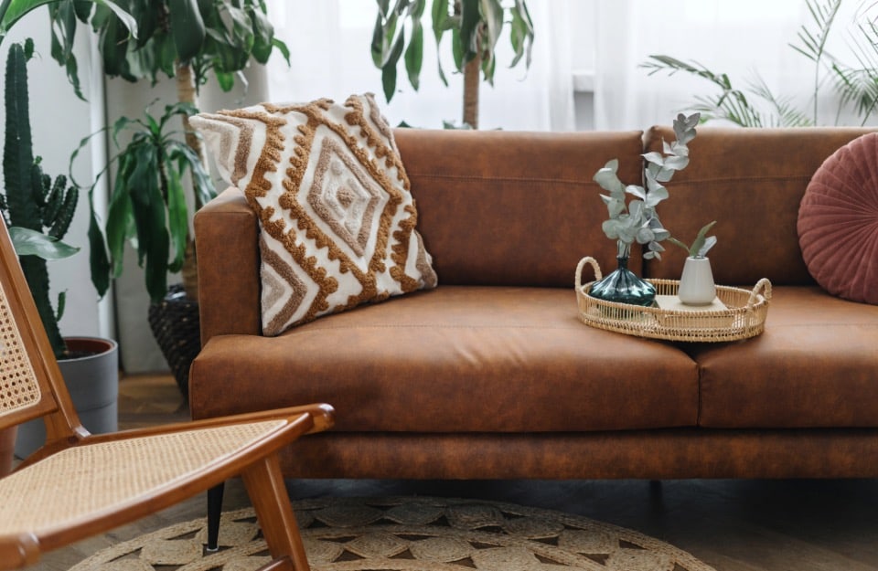 Detail of a leather sofa with geometric-patterned cushion in a 1970s-style room